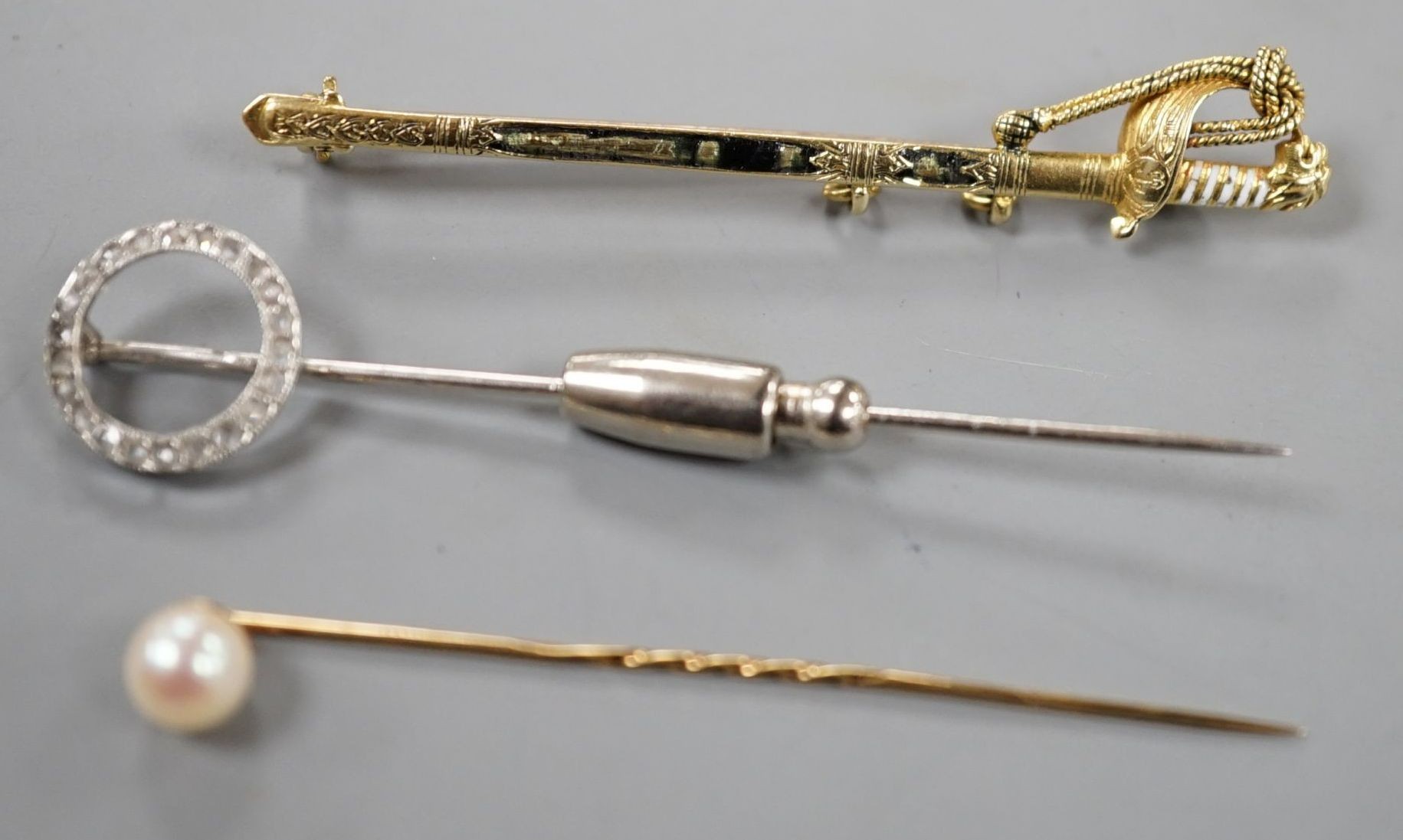 A French white metal (poincon mark for platinum) and diamond set tie pin, 64mm, gross 3.4 grams, a 15ct and enamel(a.f.) sword brooch, gross 4.7 grams and toe 9ct pins, one with cultured pearl, gross 3 grams.